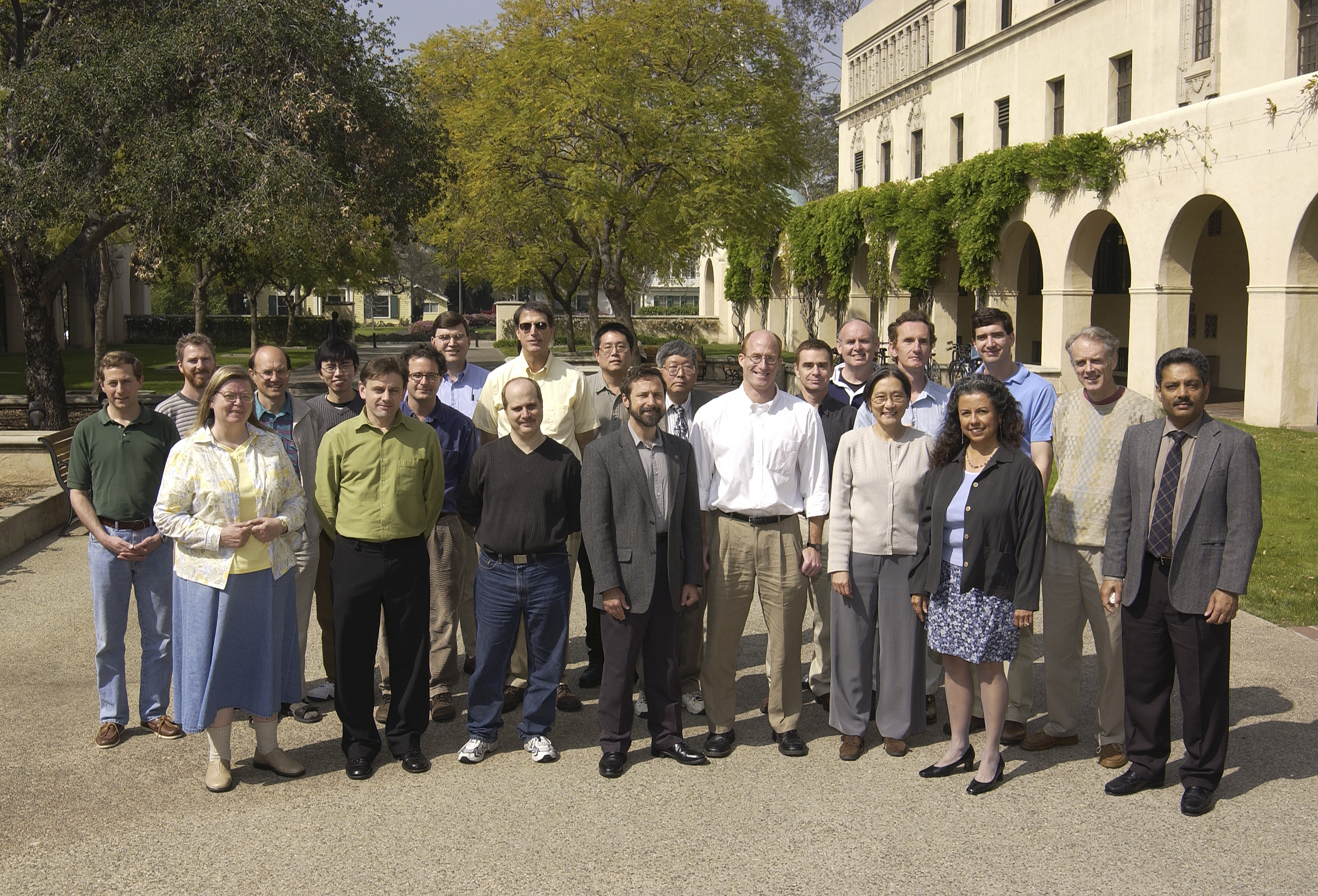 About 20 scientists, part of the earliest OCO-2 science team in 2003, pose outside on Caltech's campus on a sunny day. Dave Crisp stands in the center.