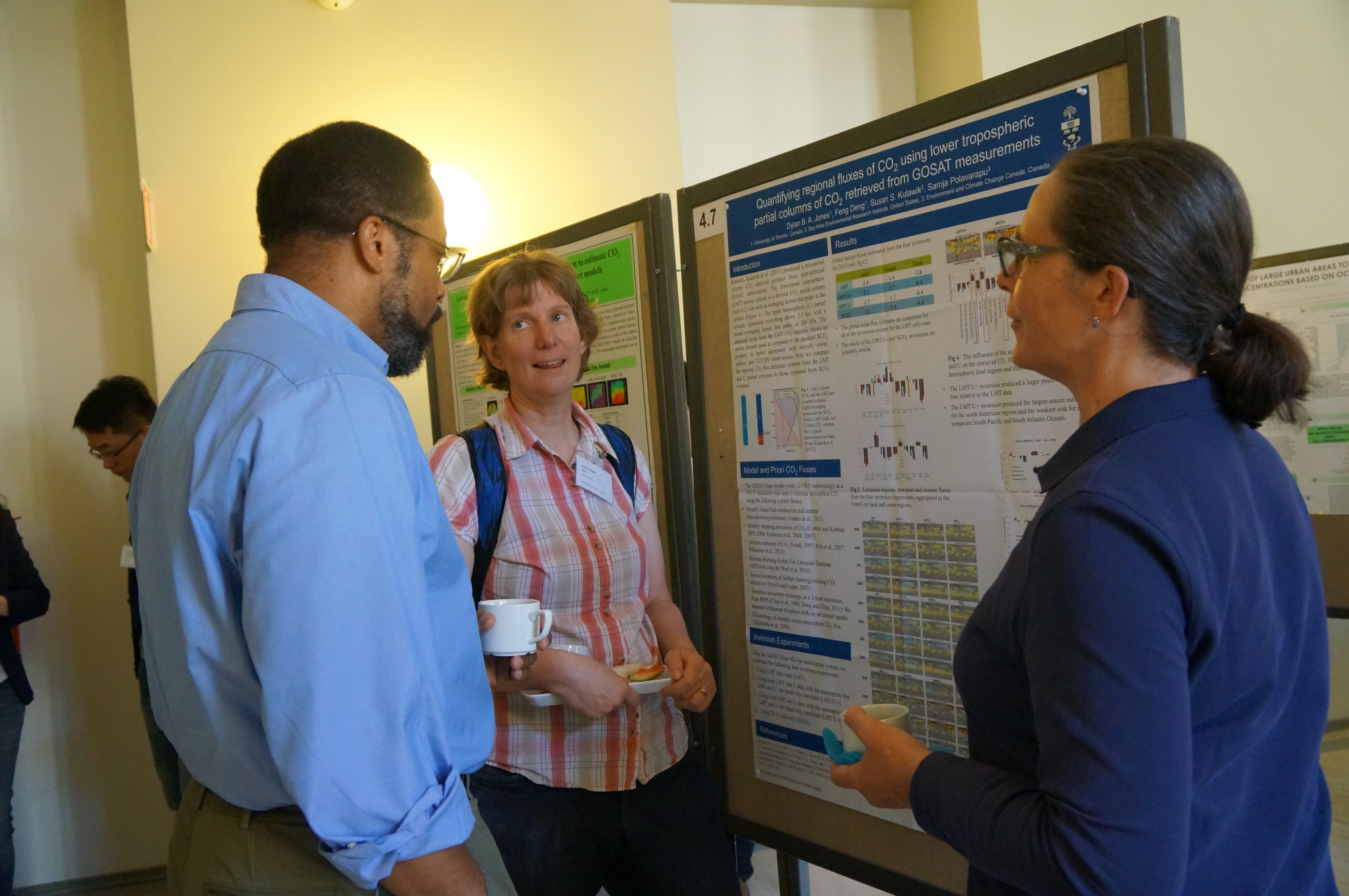 Annmarie is standing around a poster during a poster conference session with two other people. 