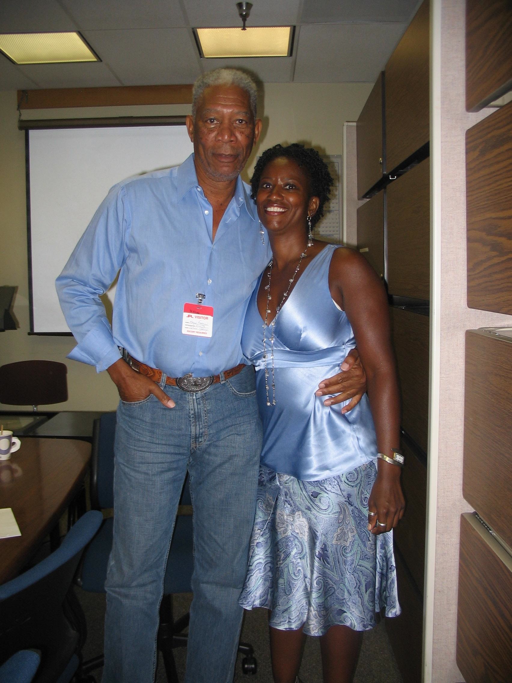 Cozette Parker and Morgan Freeman standing side by side in a room at JPL, Cozette with a big smile on her face, Morgan Freeman looking cool and calm. Both are matching in blue clothes. 