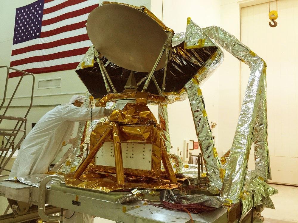  A person in a white suit working on a satellite in a clean room 